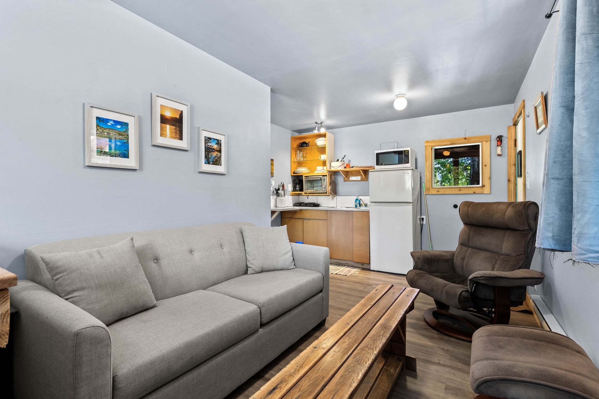 A living room with a couch , chair , table and refrigerator.