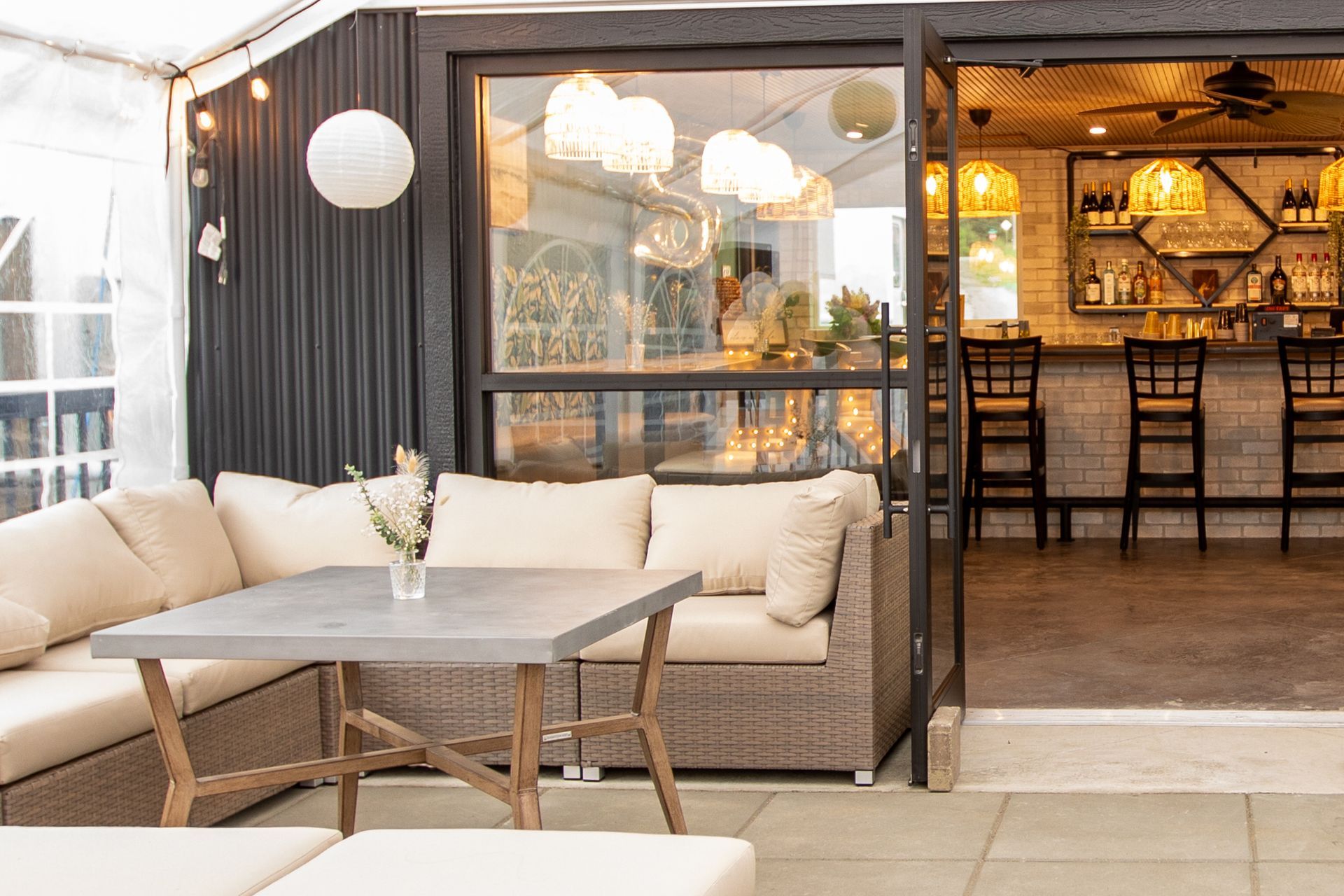 A patio with a couch , table , chairs and a bar.