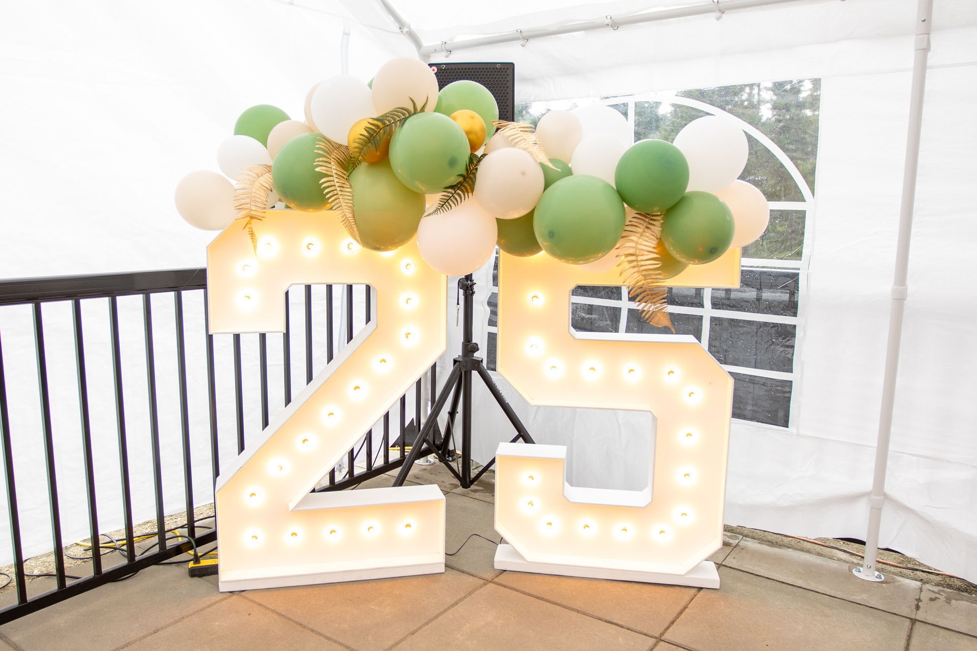 The number 25 is surrounded by balloons and lights.