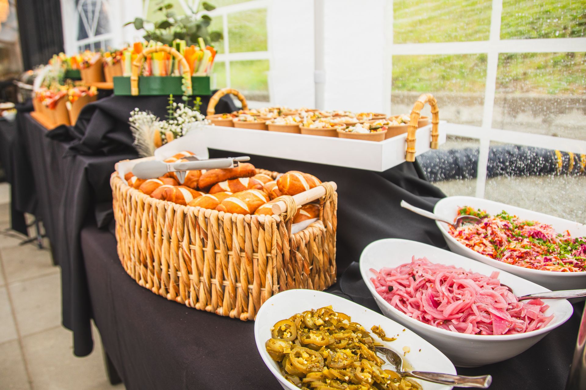 A buffet table with a basket of pretzels and bowls of food.
