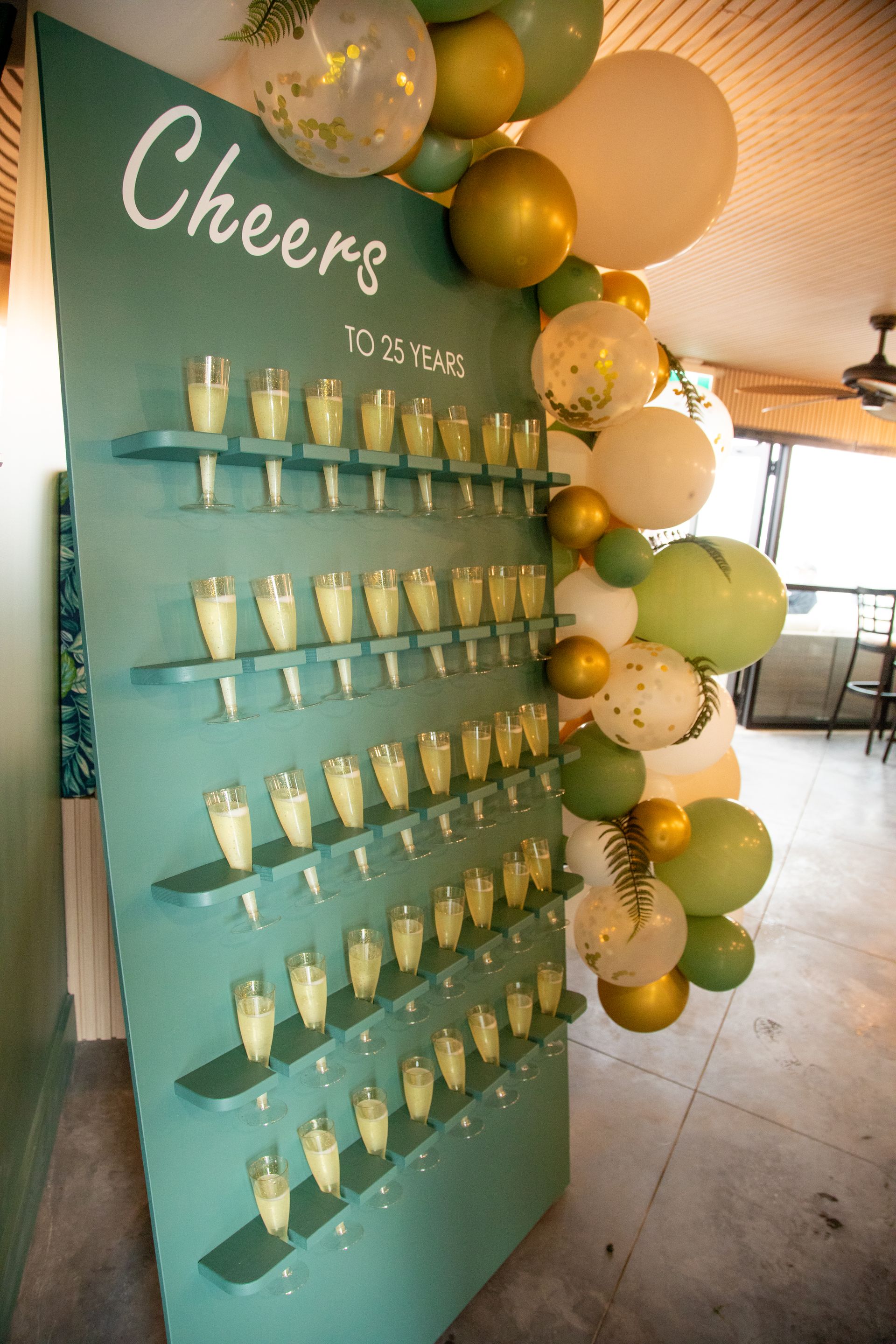 A wall filled with champagne glasses and balloons.