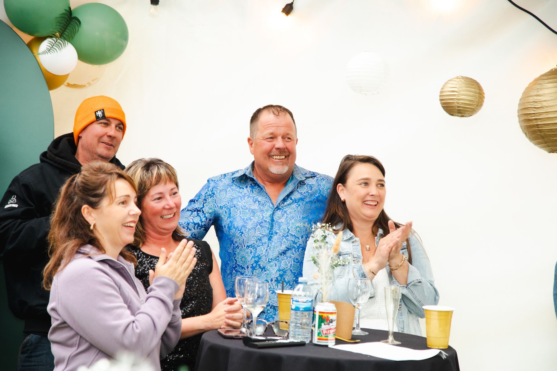 A group of people are standing around a table applauding.