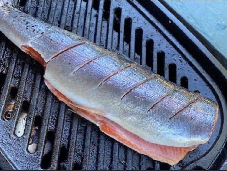 A large piece of fish is sitting on a grill