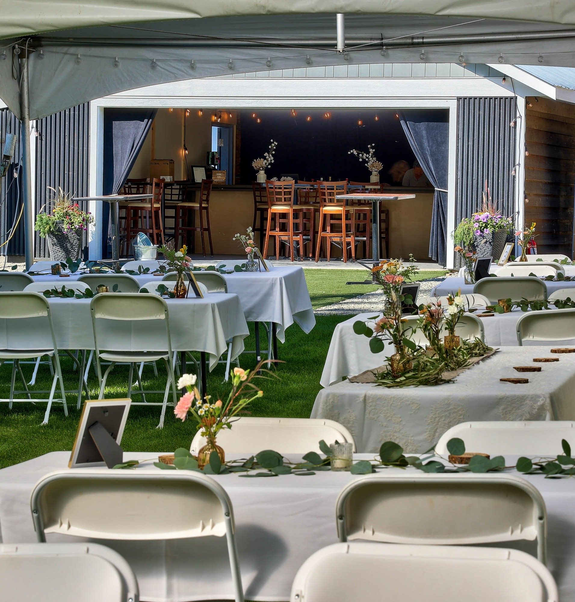 Tables and chairs under a tent with flowers on them