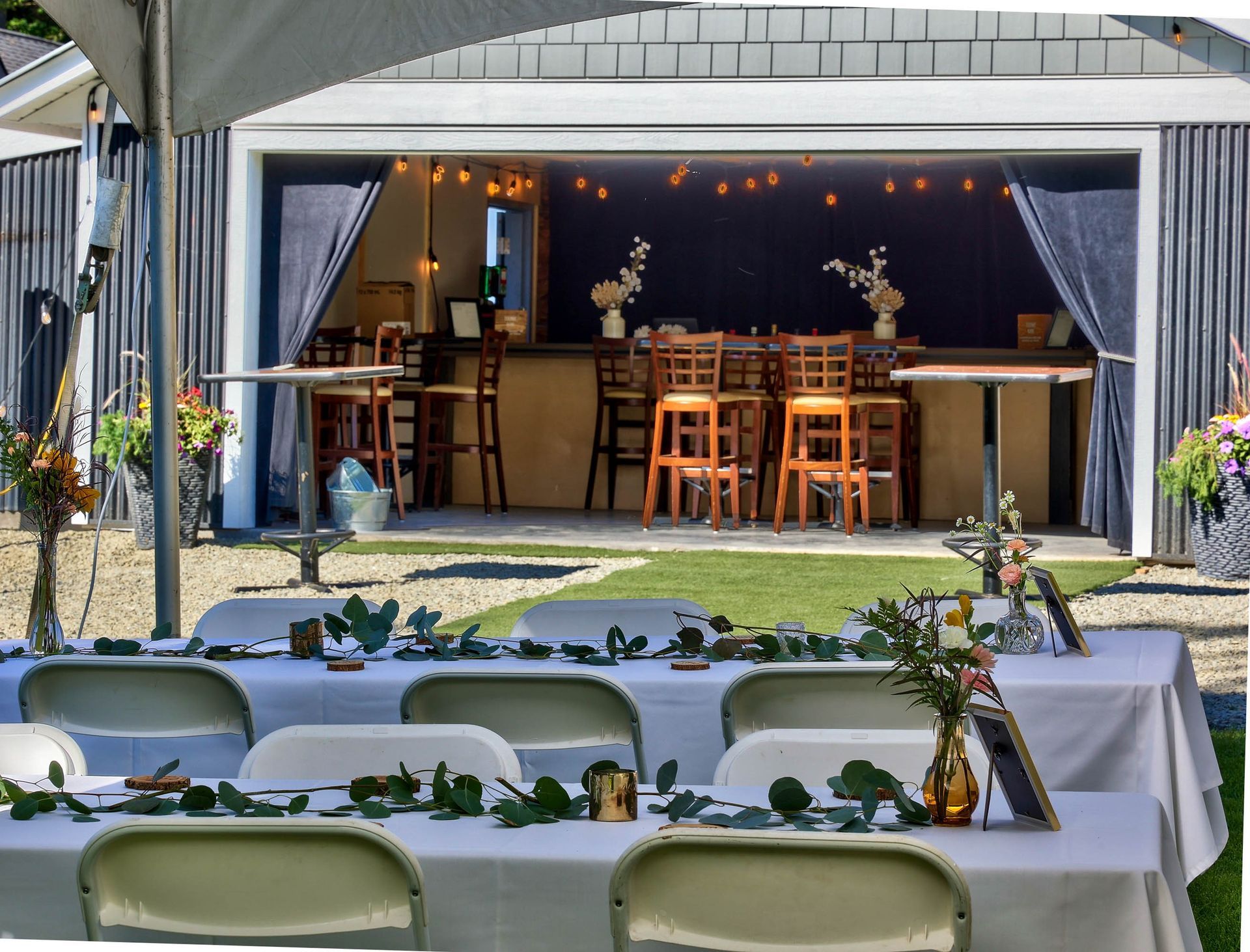 Tables and chairs are set up in front of a garage door.