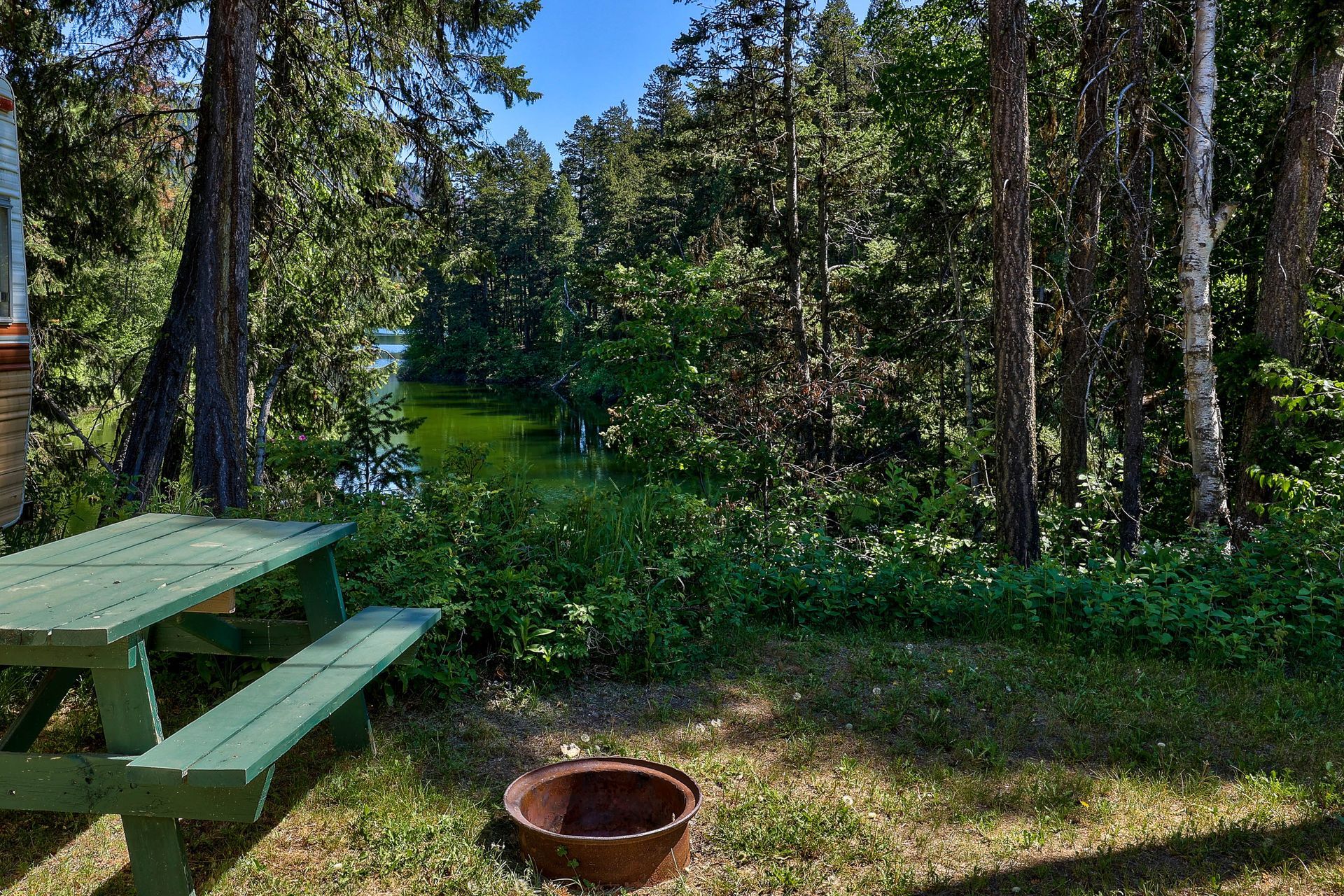 There is a picnic table and a fire pit in the middle of the woods.