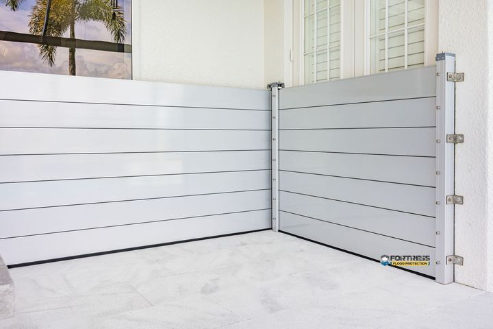 Two silver flood barriers installed at a building entrance, protecting from rising water.