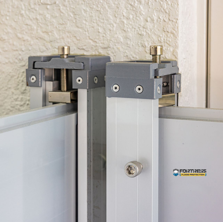 Two gray brackets on aluminum frame, with a screw mechanism. Wall backdrop.