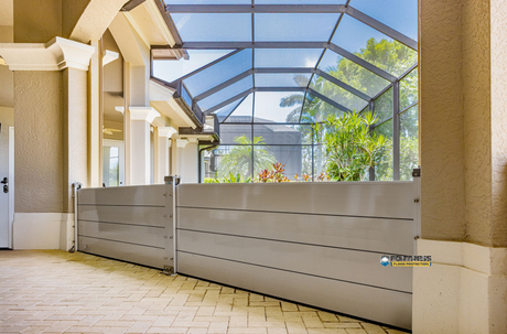 A flood barrier protects an outdoor space, featuring a high metal wall, under a screened enclosure.