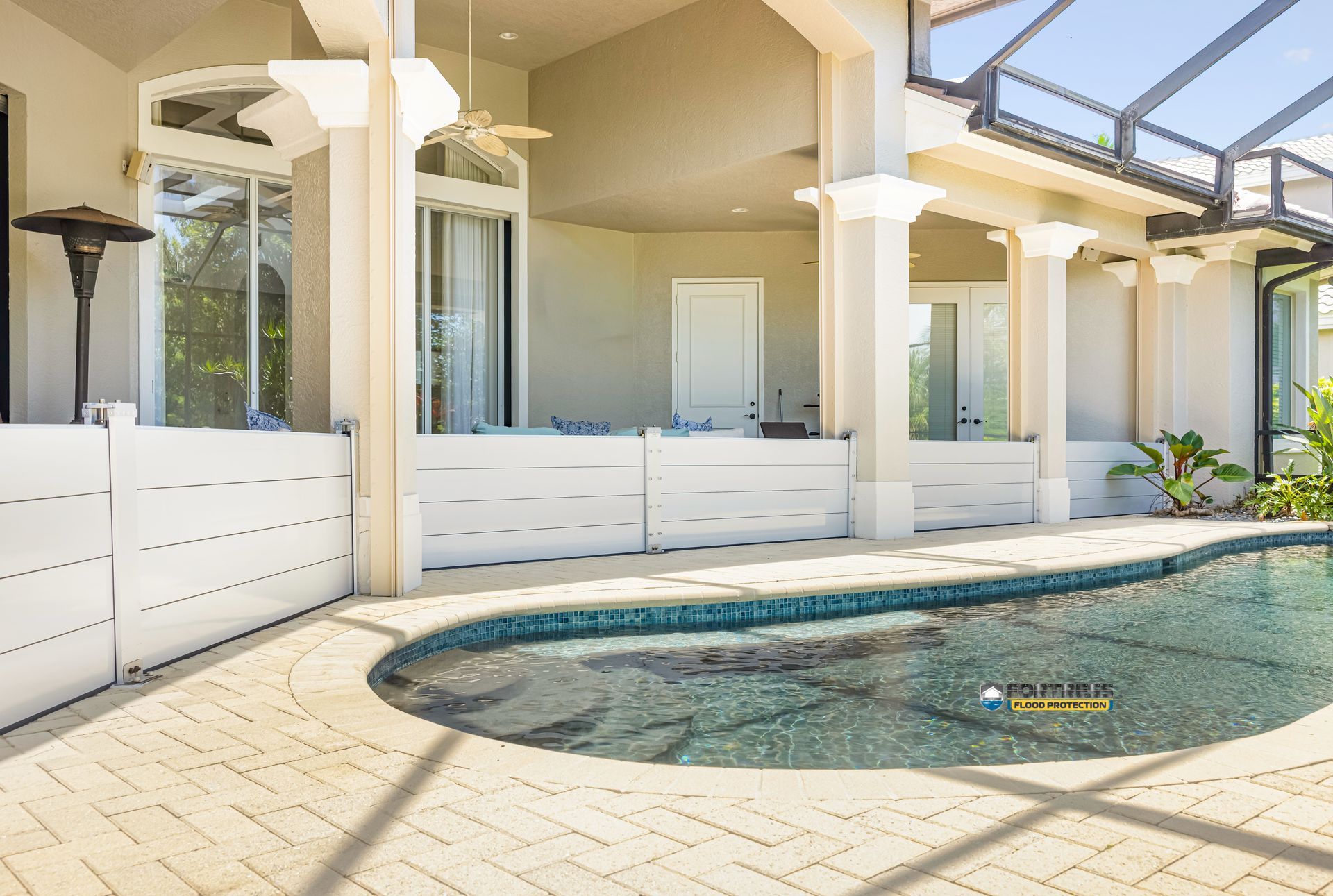 Poolside patio with pool, white pillars, and house.