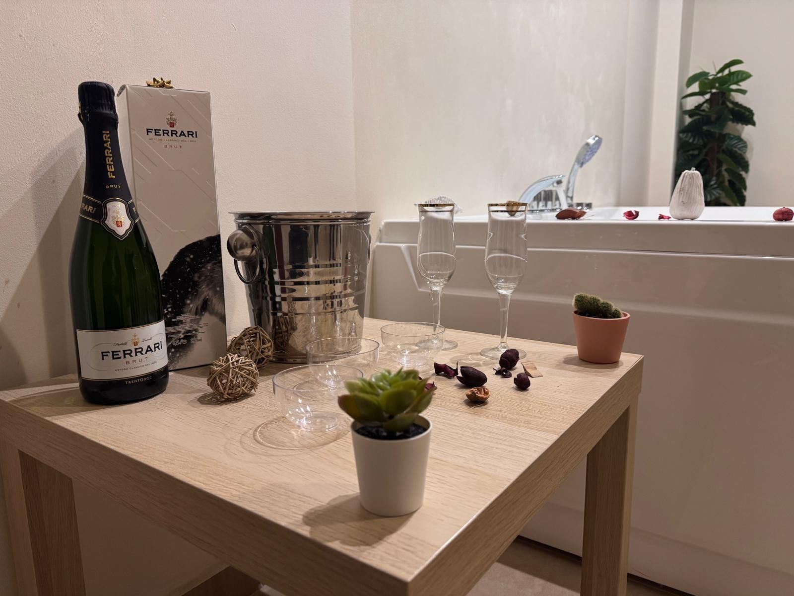 Un tavolo con una bottiglia di champagne e dei bicchieri davanti a una vasca da bagno.