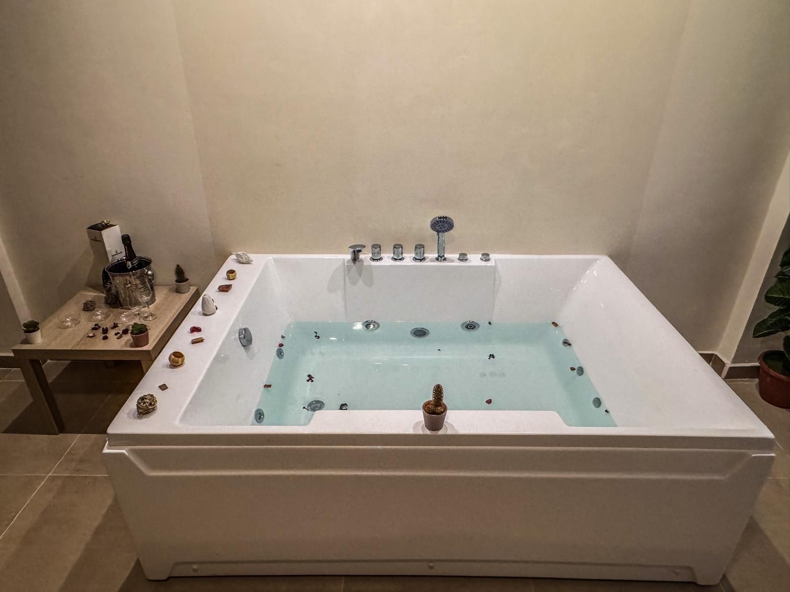 Una grande vasca idromassaggio bianca è posizionata in un bagno, accanto a un tavolo.