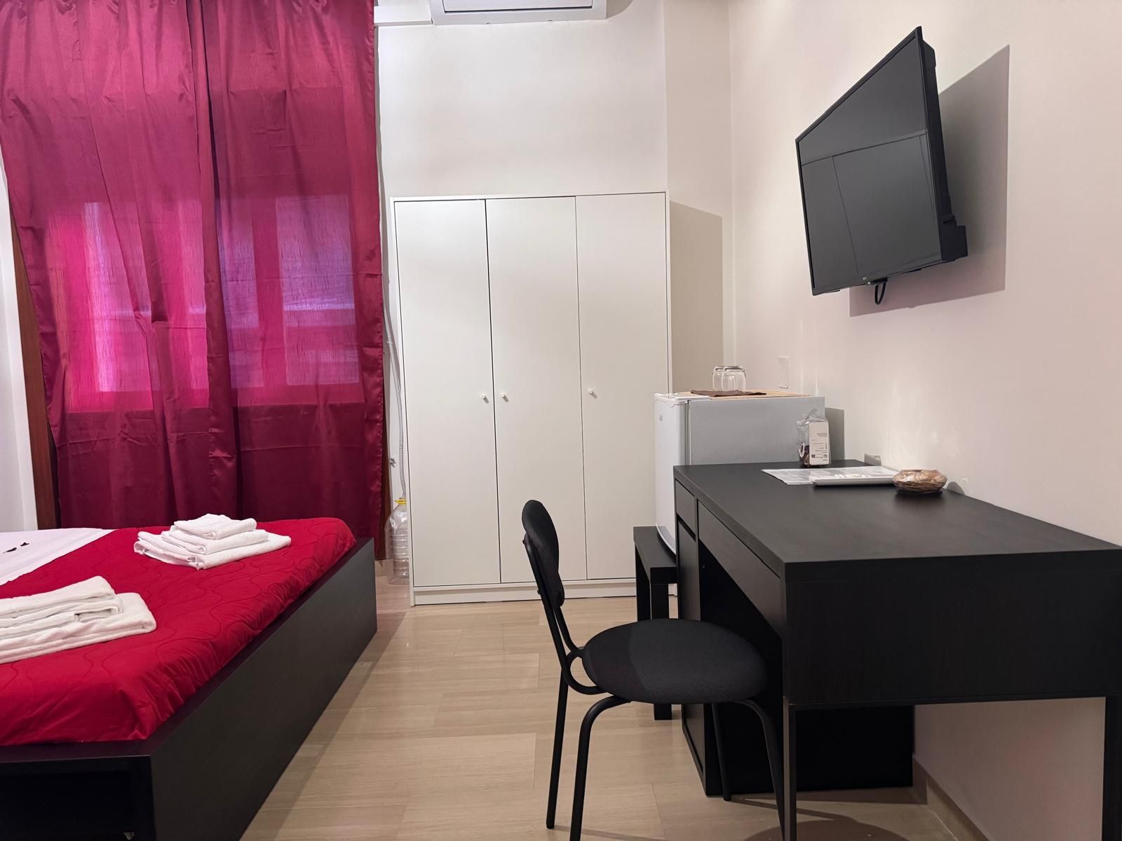 Una camera d'albergo con un letto, una scrivania, una sedia e una televisione