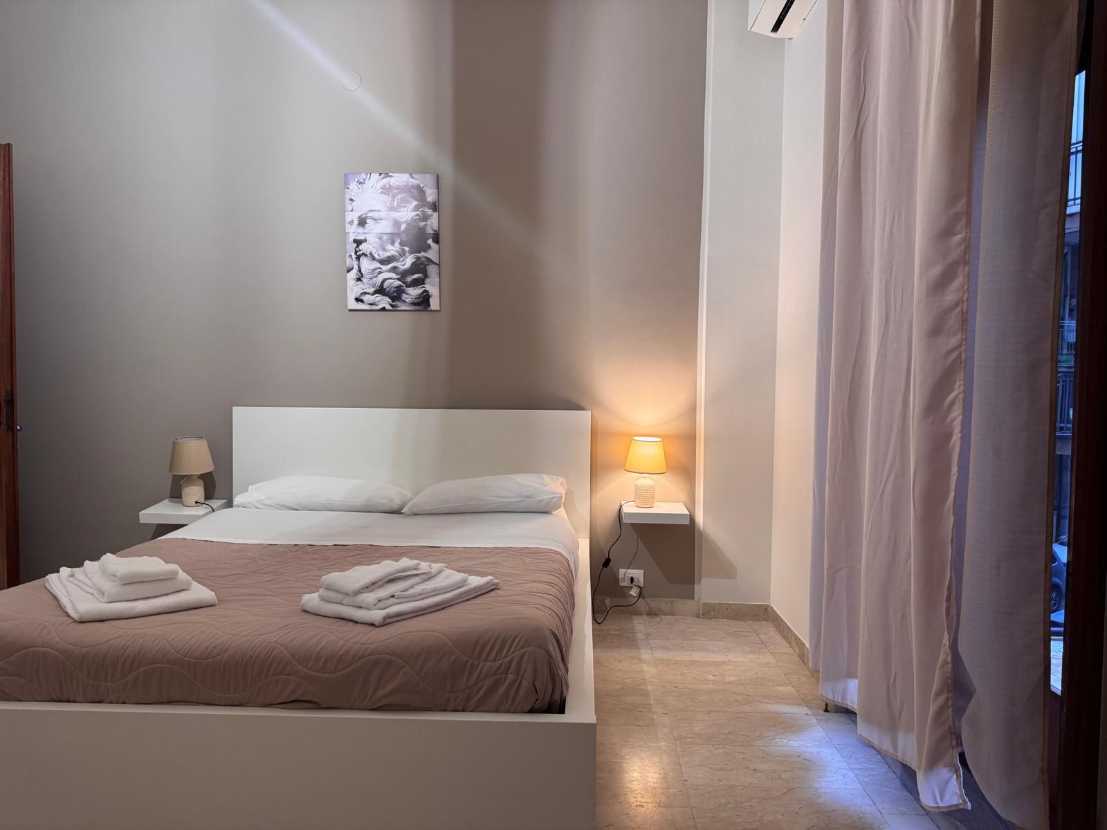 Una camera da letto con un letto, due lampade, un quadro sul muro e una finestra.