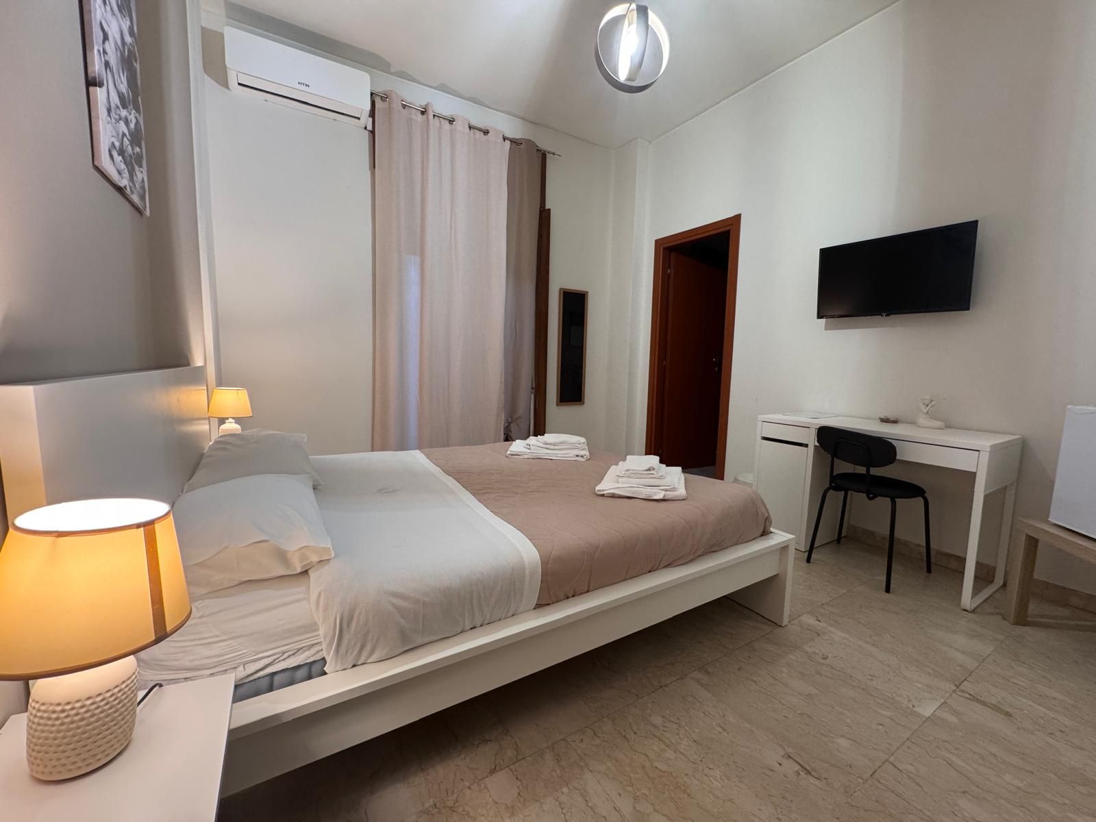 Una camera da letto con due letti, una scrivania e una televisione.