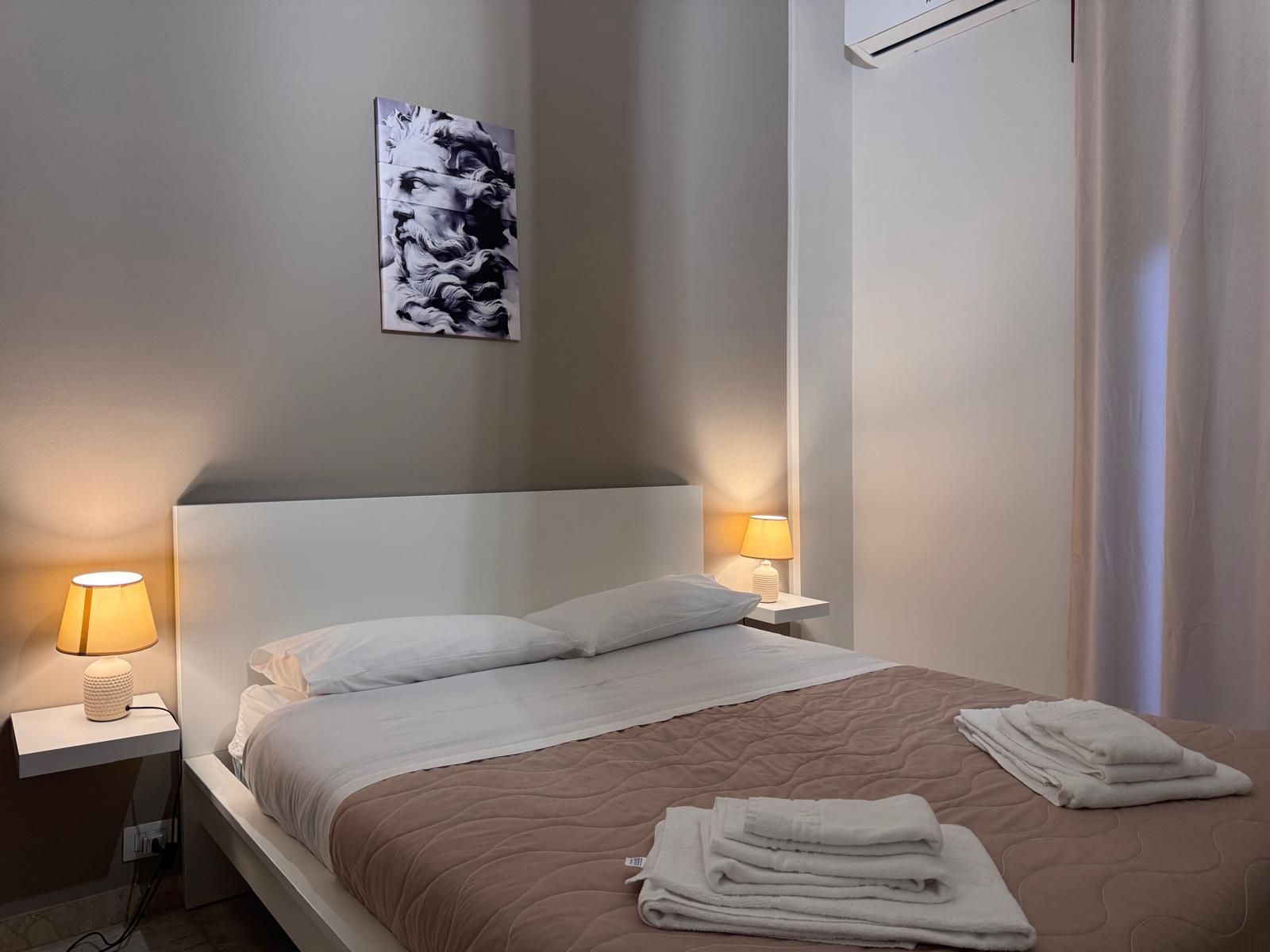 Una camera da letto con un letto, lampade e un quadro sulla parete sopra il letto.