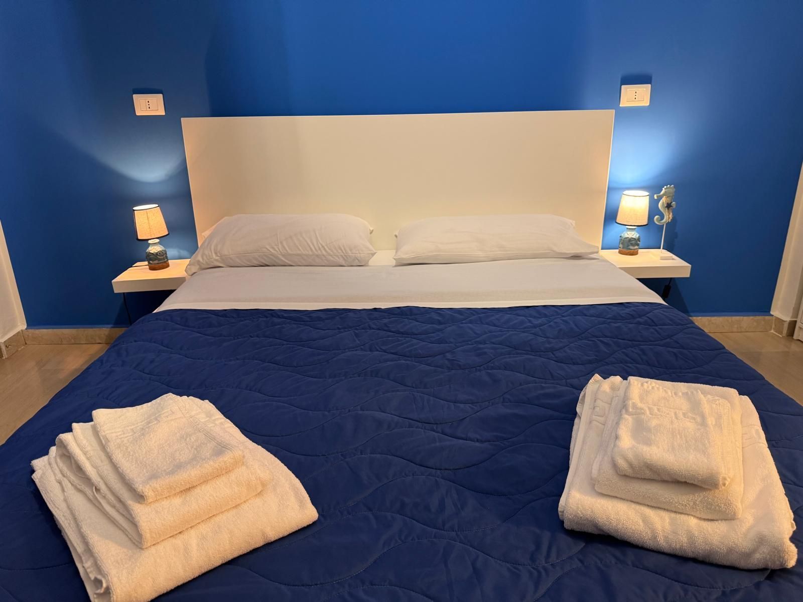 Un letto con una coperta blu e asciugamani bianchi sopra