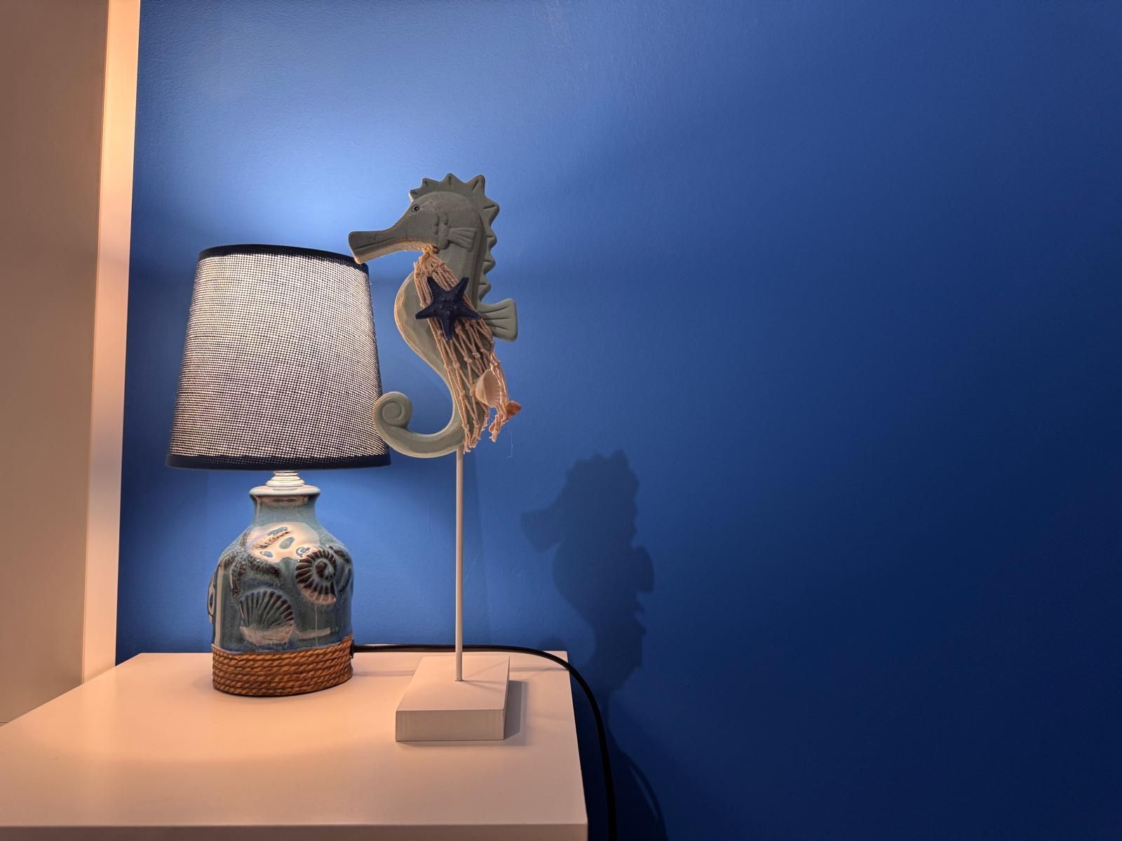 Una lampada con un cavalluccio marino è su un tavolo davanti a una parete blu.