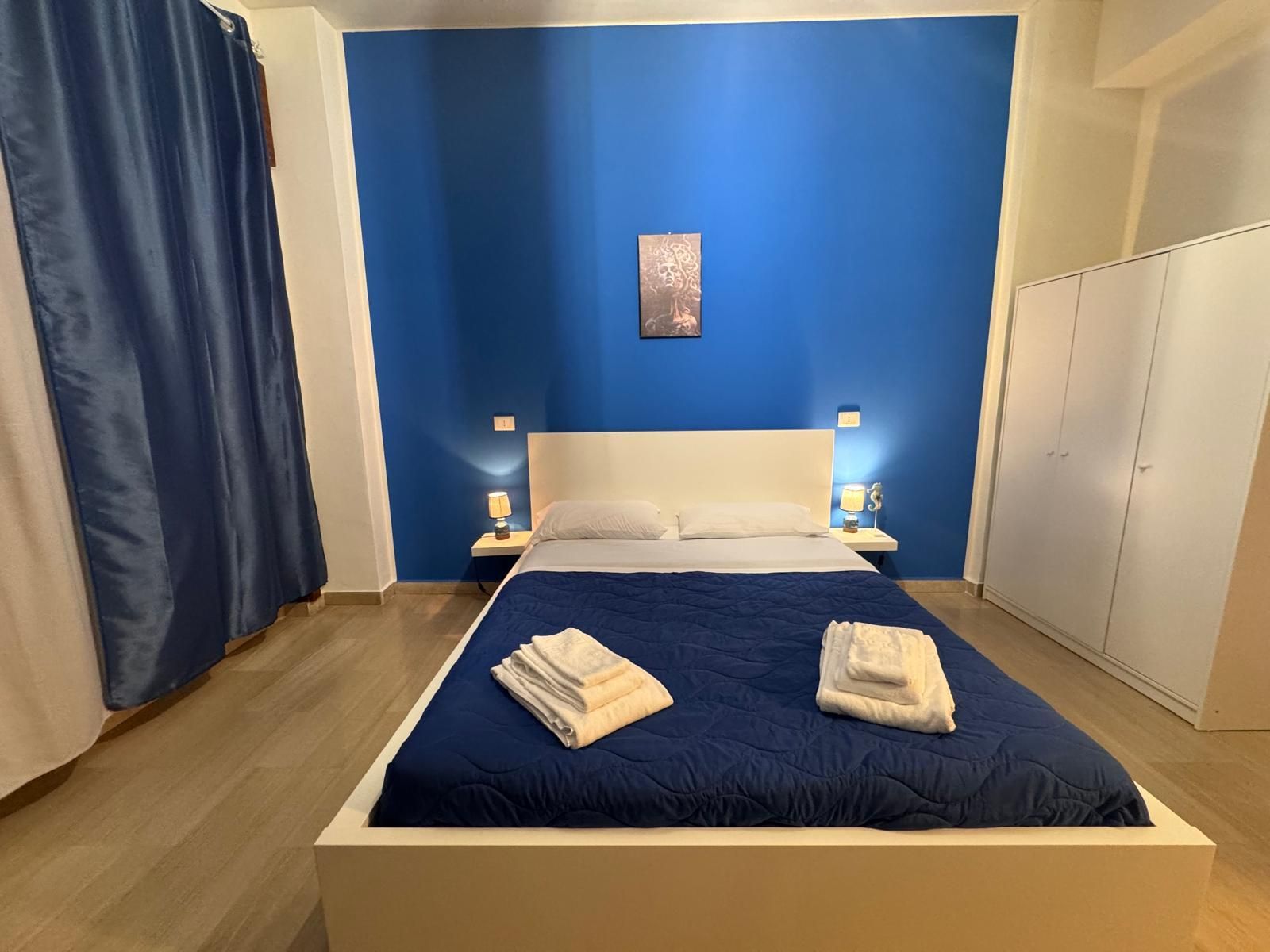 Una camera da letto con una parete blu e un letto bianco