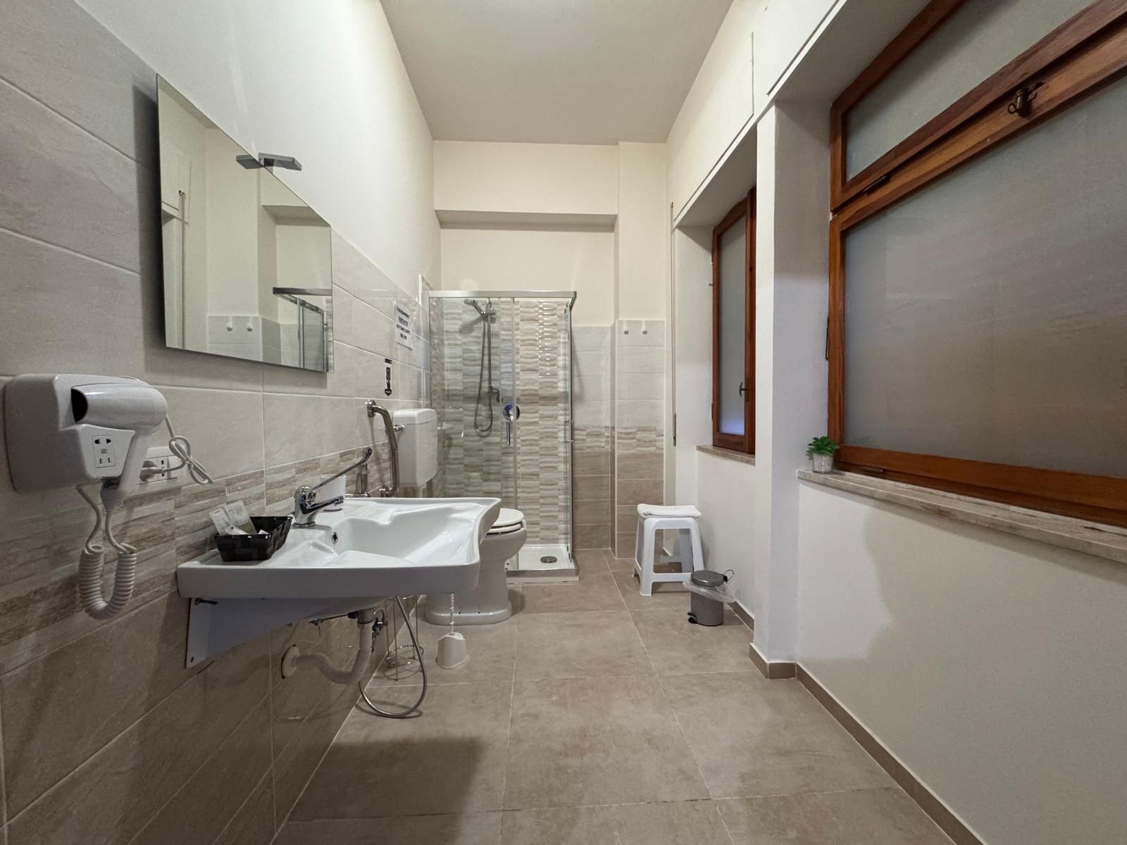 Un bagno con lavandino, wc, doccia e specchio.