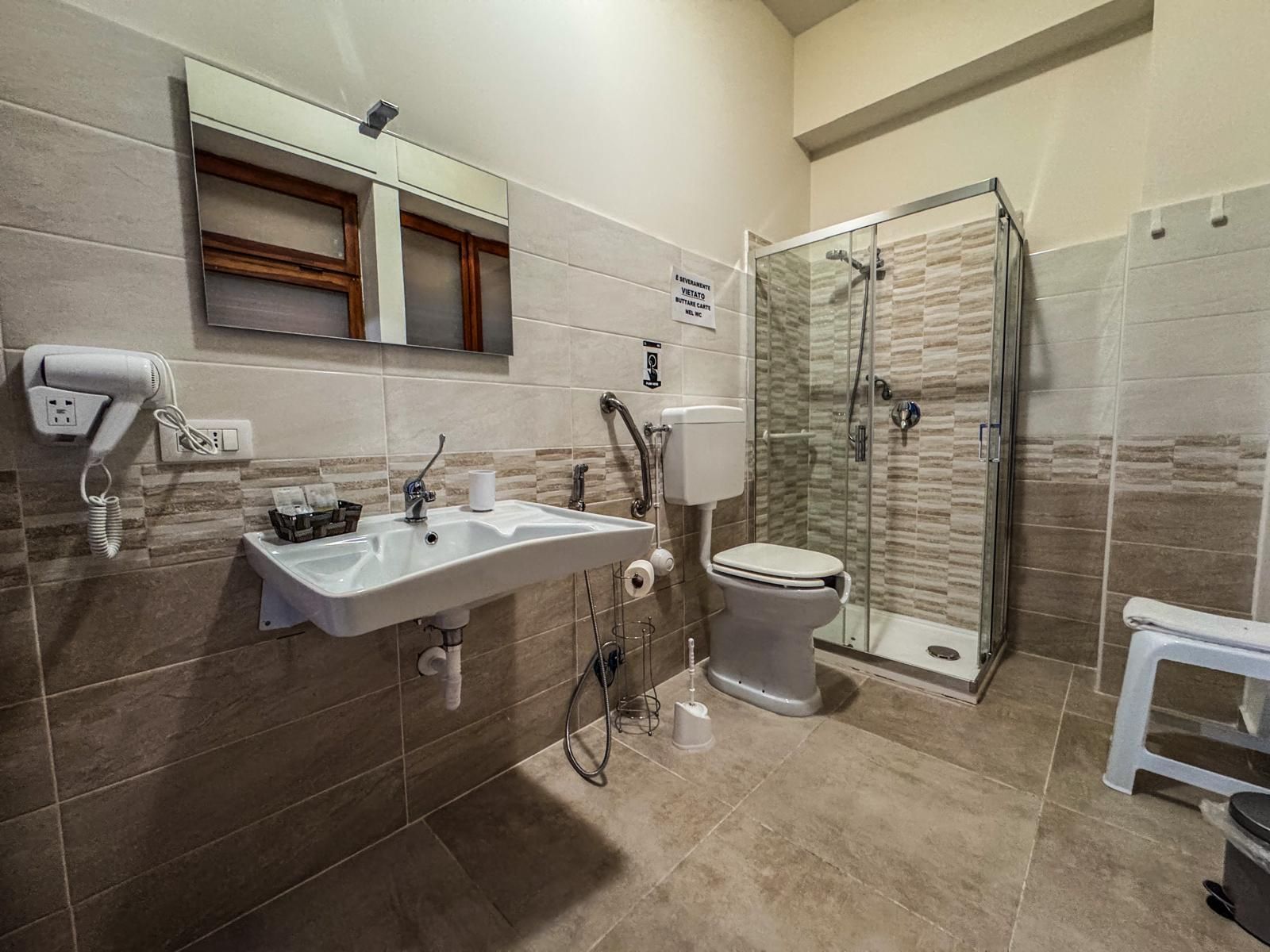 Un bagno con lavandino, wc, doccia e specchio.