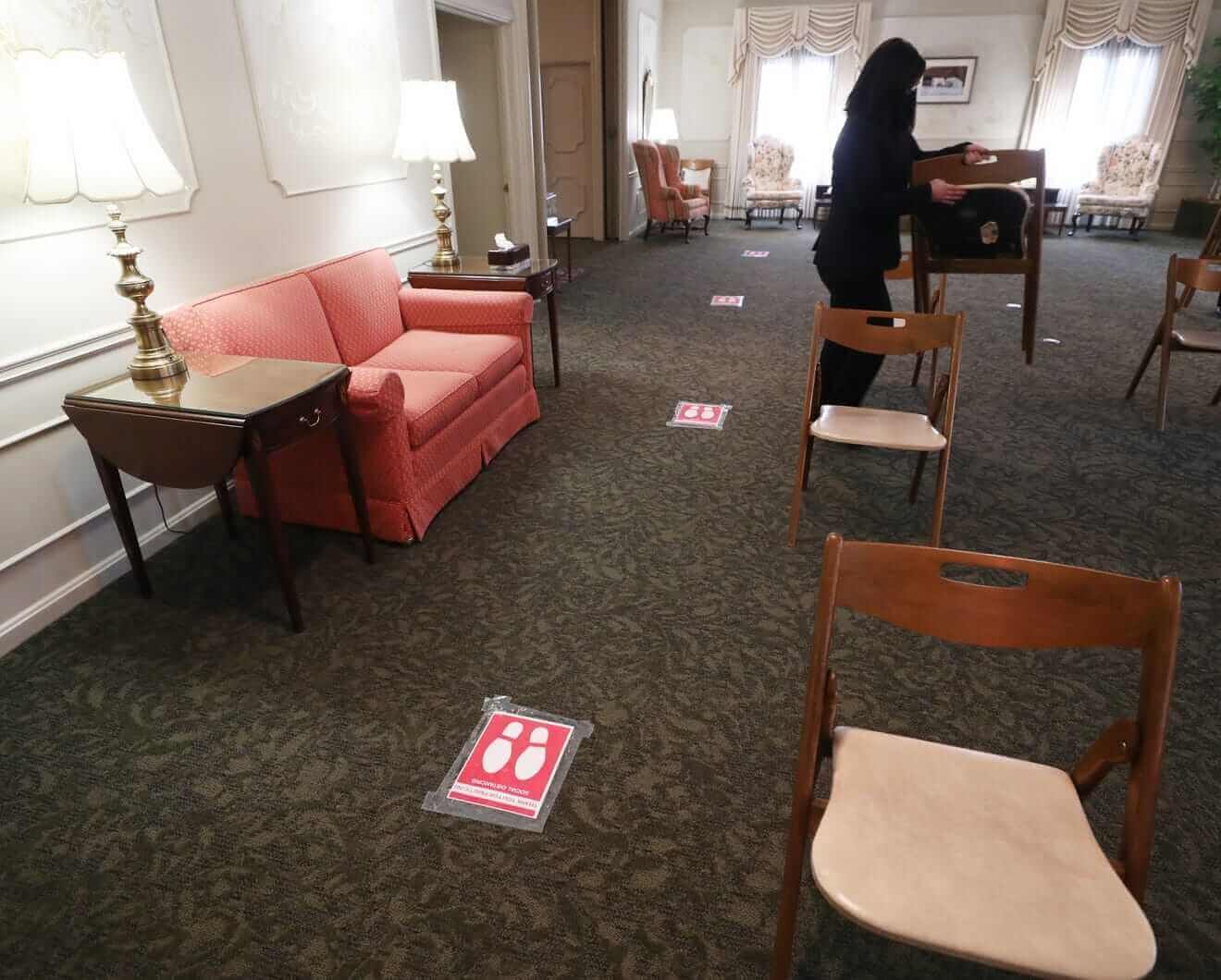 A woman is standing in a room with chairs and a couch.