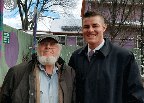 Two men are posing for a picture together in front of a building.