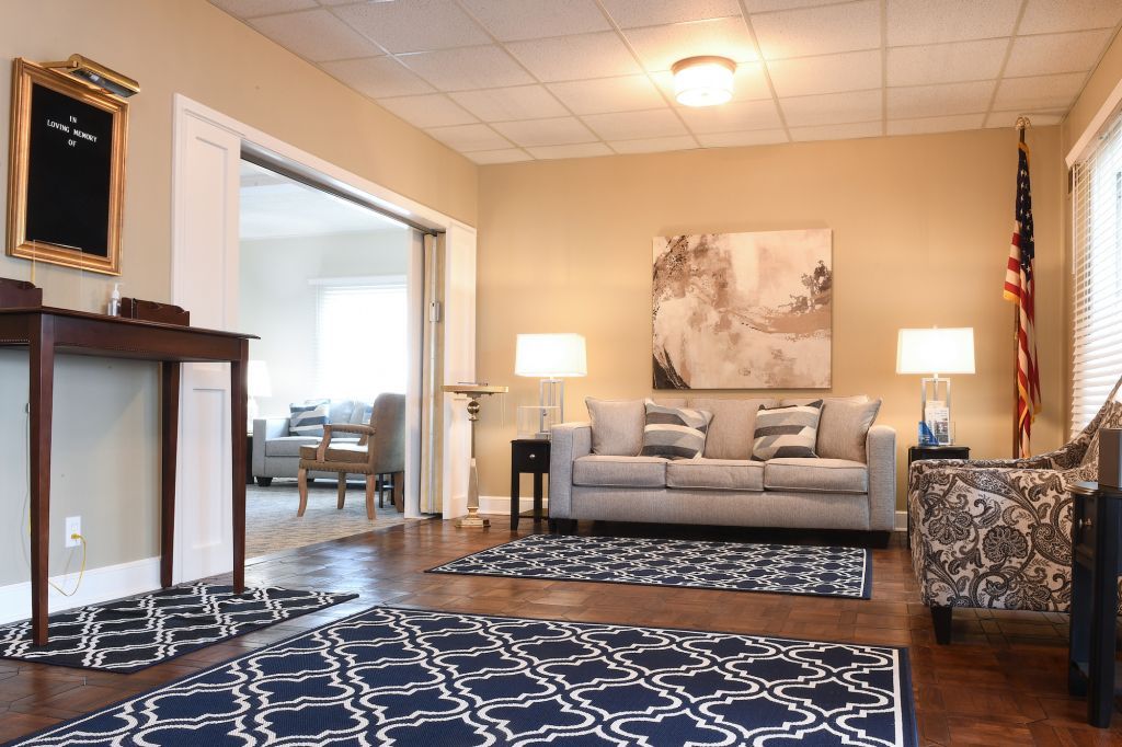 A living room with a couch , chairs , lamps and a rug.