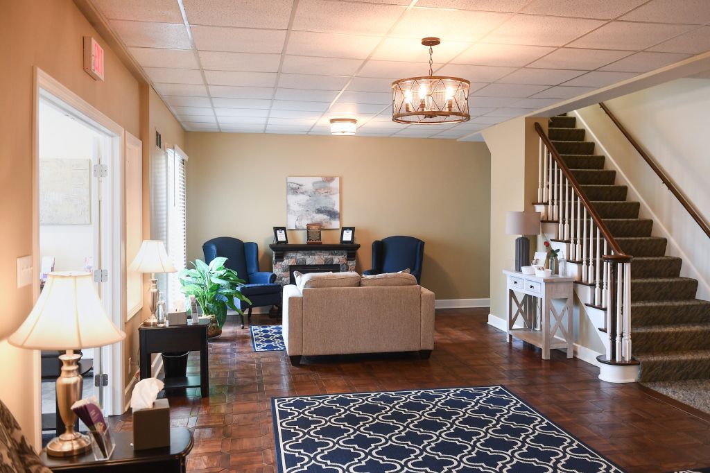 A living room with a rug and stairs in the background