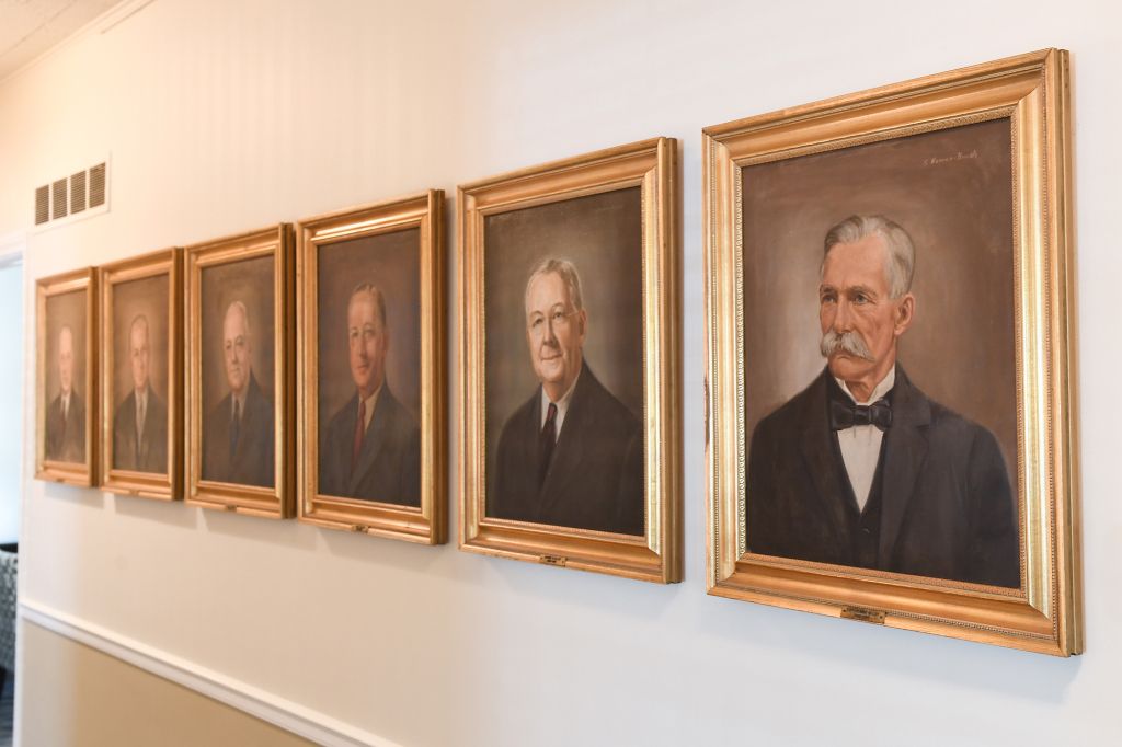 A row of framed portraits of men on a wall