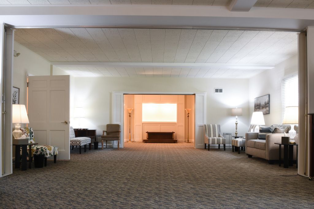 A living room with a couch , chairs , lamps and a fireplace.