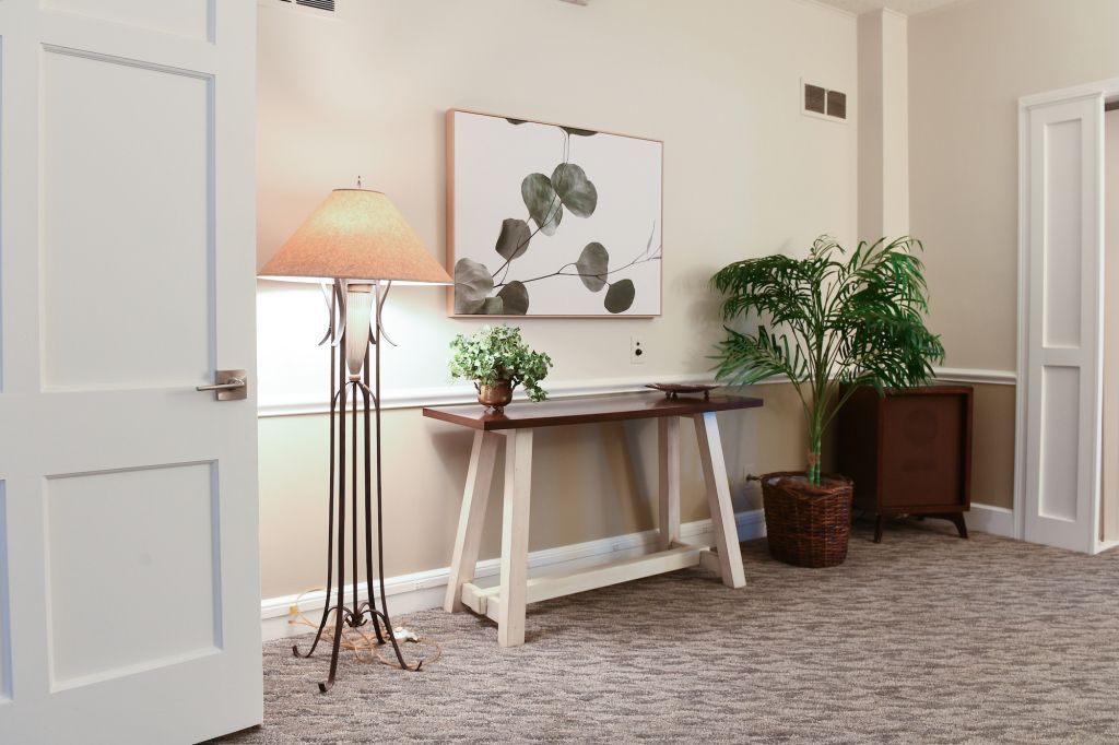 A living room with a table , lamp , and potted plant.