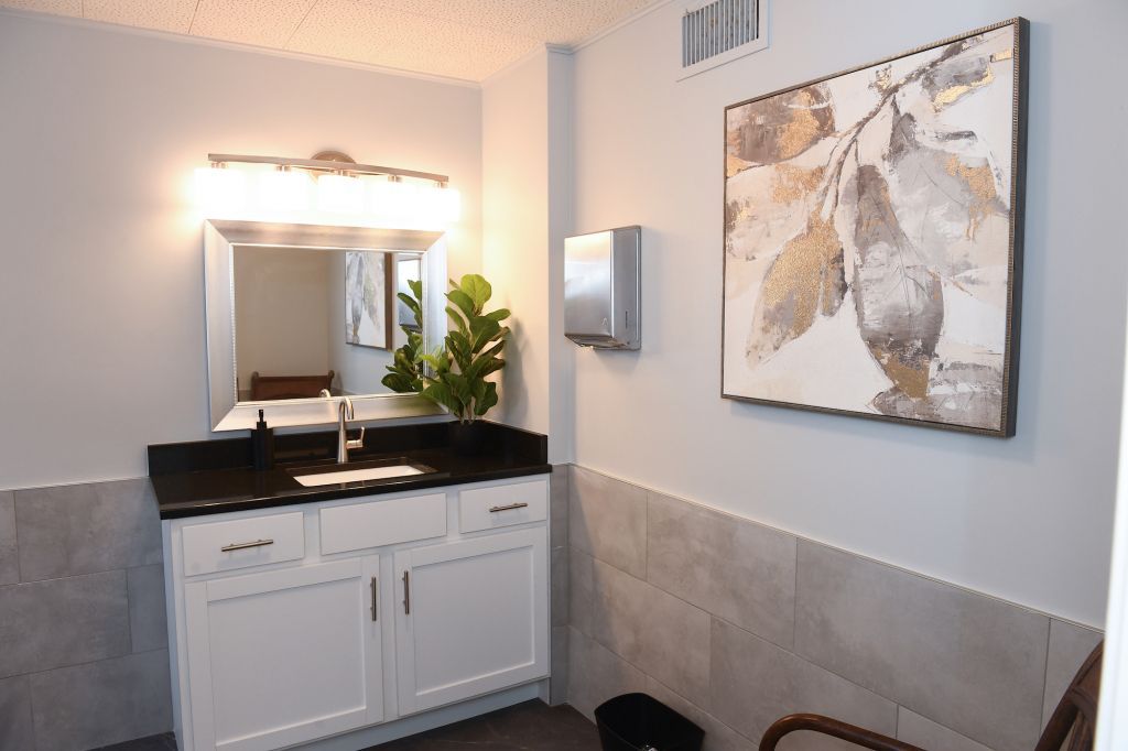 A bathroom with a sink , mirror and painting on the wall.