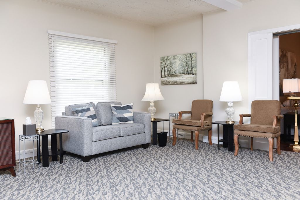A living room with a couch , chairs , tables and lamps.