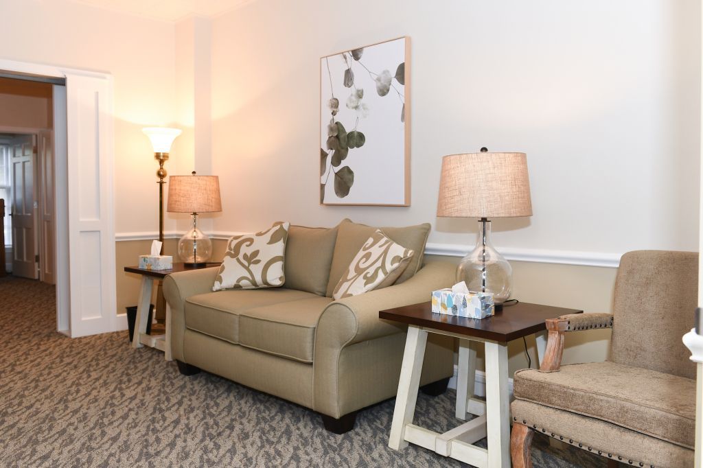 A living room with a couch , chair , table and lamp.
