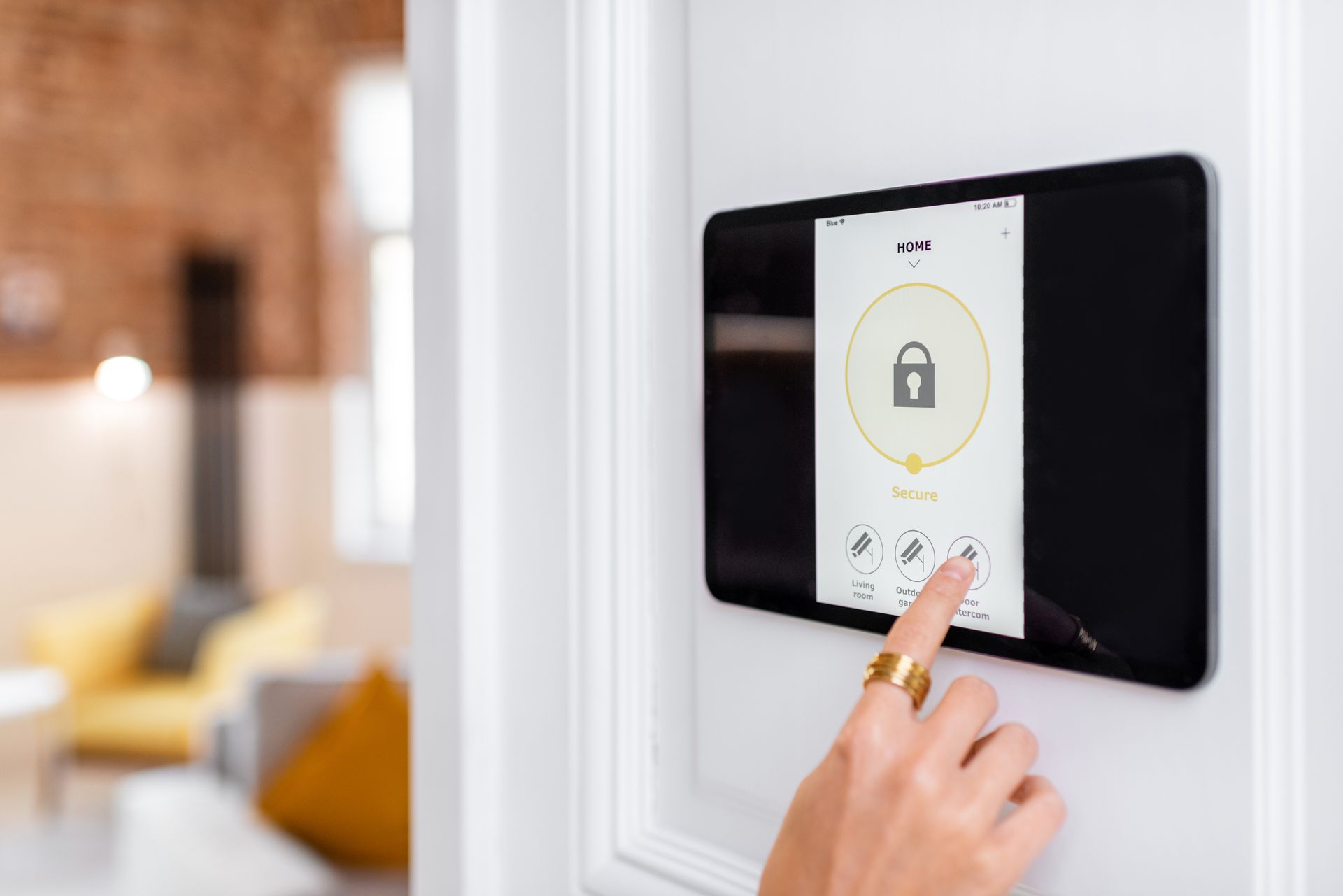 A person's hand controls the alarm system with a digital touch screen panel installed on the wall.