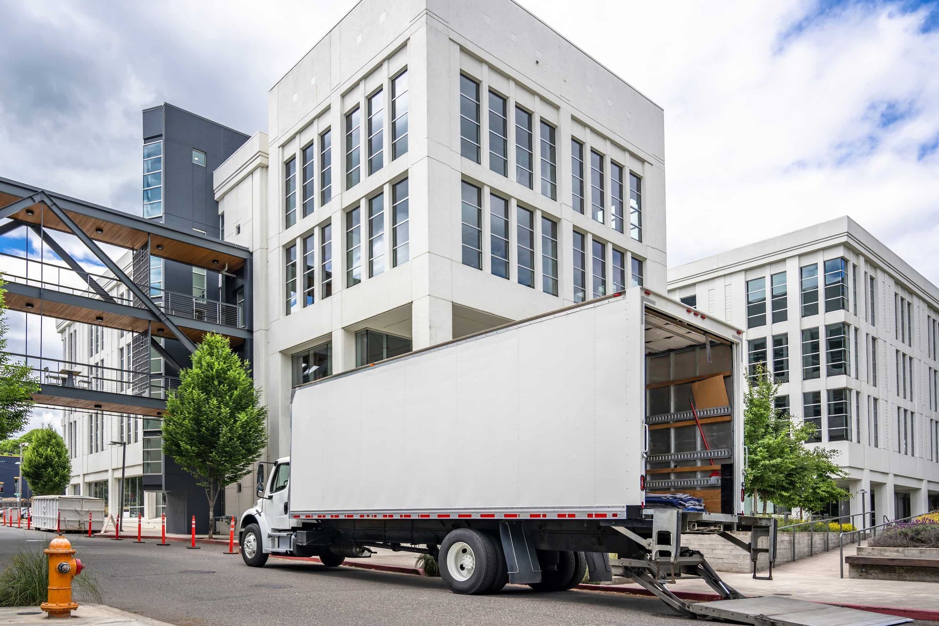 Moving truck backed up to a modern white building with large windows.