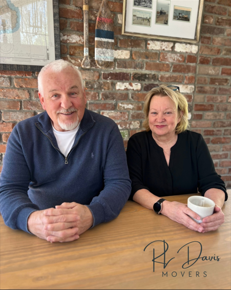 Owners sitting at a table with brick wall background.