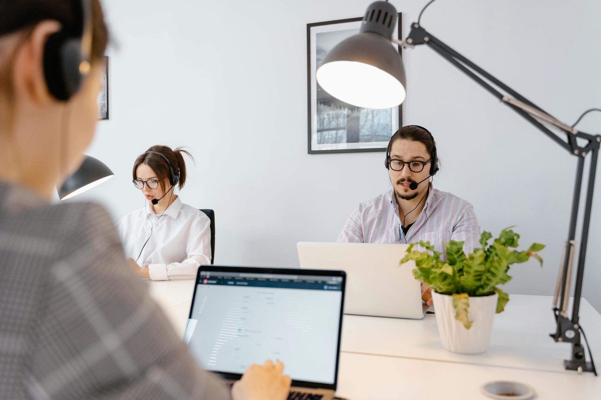A man wearing a headset is sitting at a desk with a laptop.