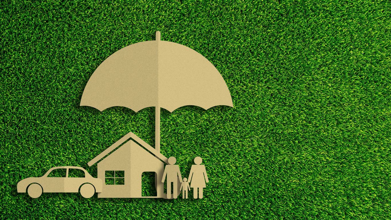 cutouts representing umbrella, auto, home, and life insurance lay on grass