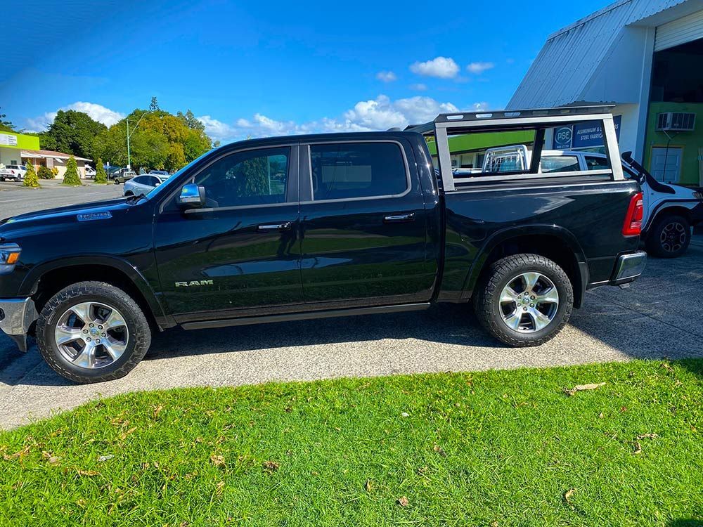 A black dodge ram truck is parked in a driveway next to a building  — PSE Stainless Steel Fabrications in Manunda, QLD
