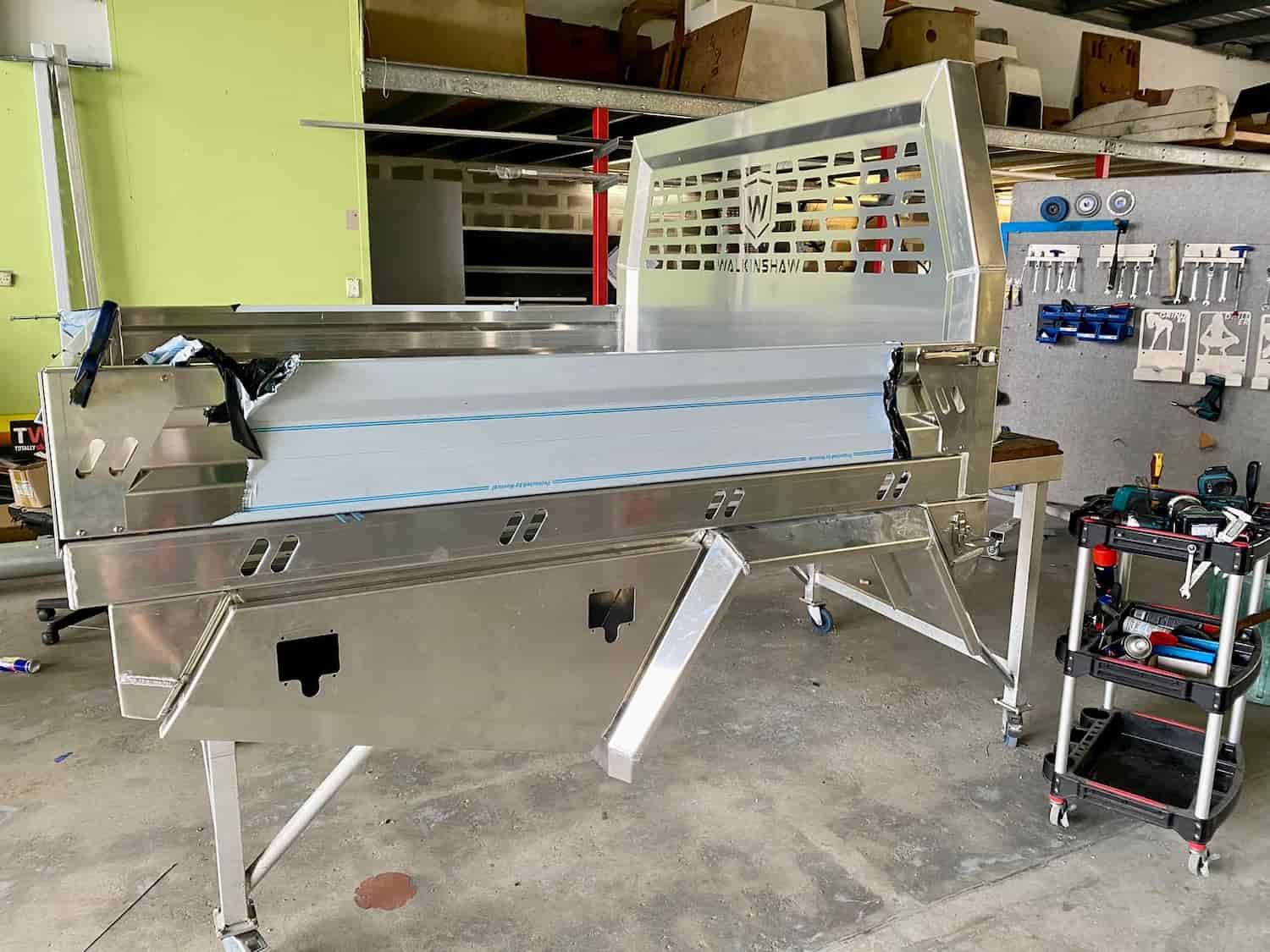 A Stainless Steel Table is Sitting in a Garage Next to a Cart — PSE Stainless Steel Fabrications In Manunda, QLD