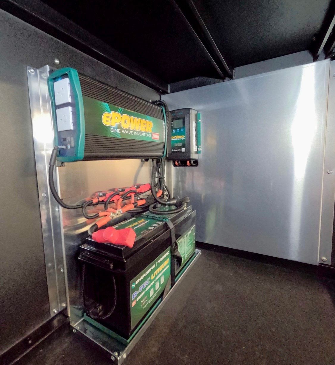 Two batteries are sitting on a shelf next to a charger  — PSE Stainless Steel Fabrications in Manunda, QLD