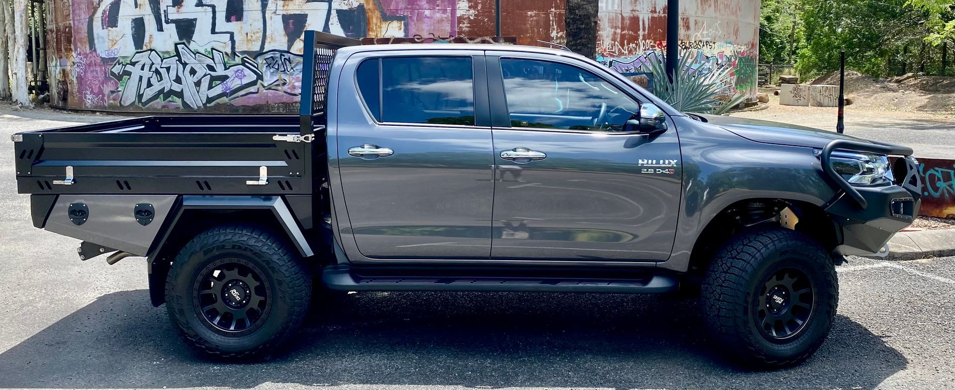 A gray truck with a tray on the back is parked in front of a building with graffiti on it  — PSE Stainless Steel Fabrications in Manunda, QLD