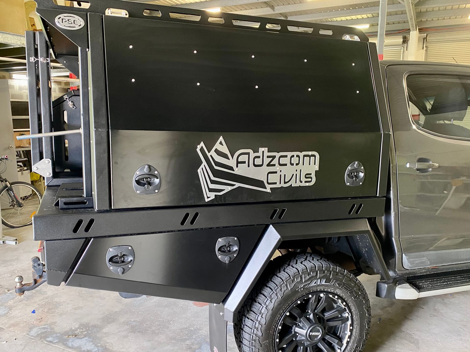 A black truck with a canopy on top of it is parked in a garage  — PSE Stainless Steel Fabrications in Manunda, QLD