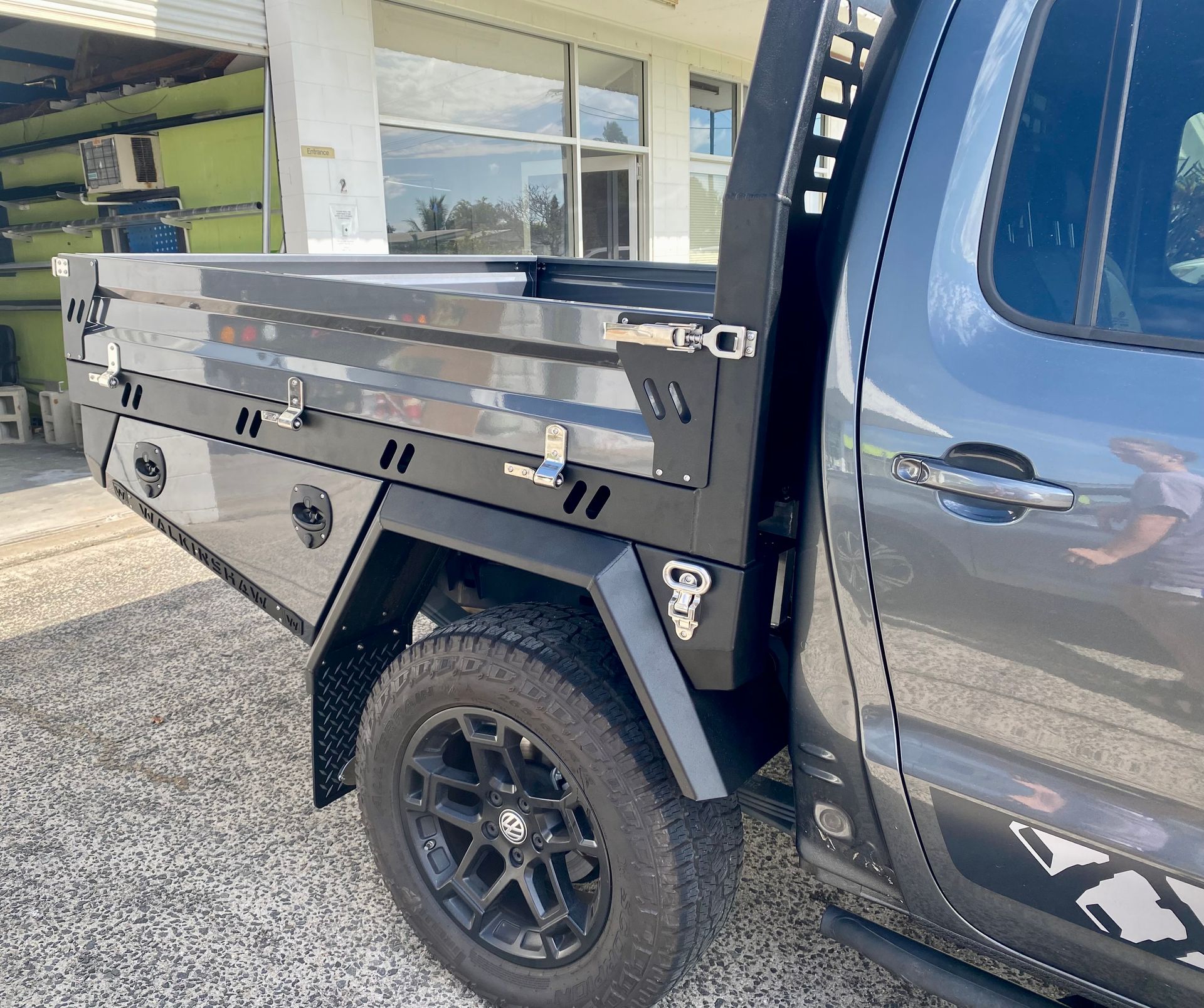 A black truck with a flat bed is parked in front of a building  — PSE Stainless Steel Fabrications in Manunda, QLD