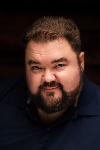 A man with a beard and a blue shirt is smiling for the camera.