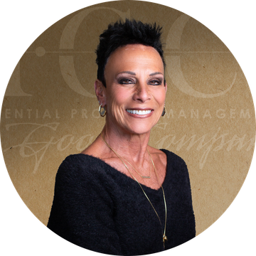 Woman with short black hair smiles, wearing a black top, gold necklace, and hoop earrings.