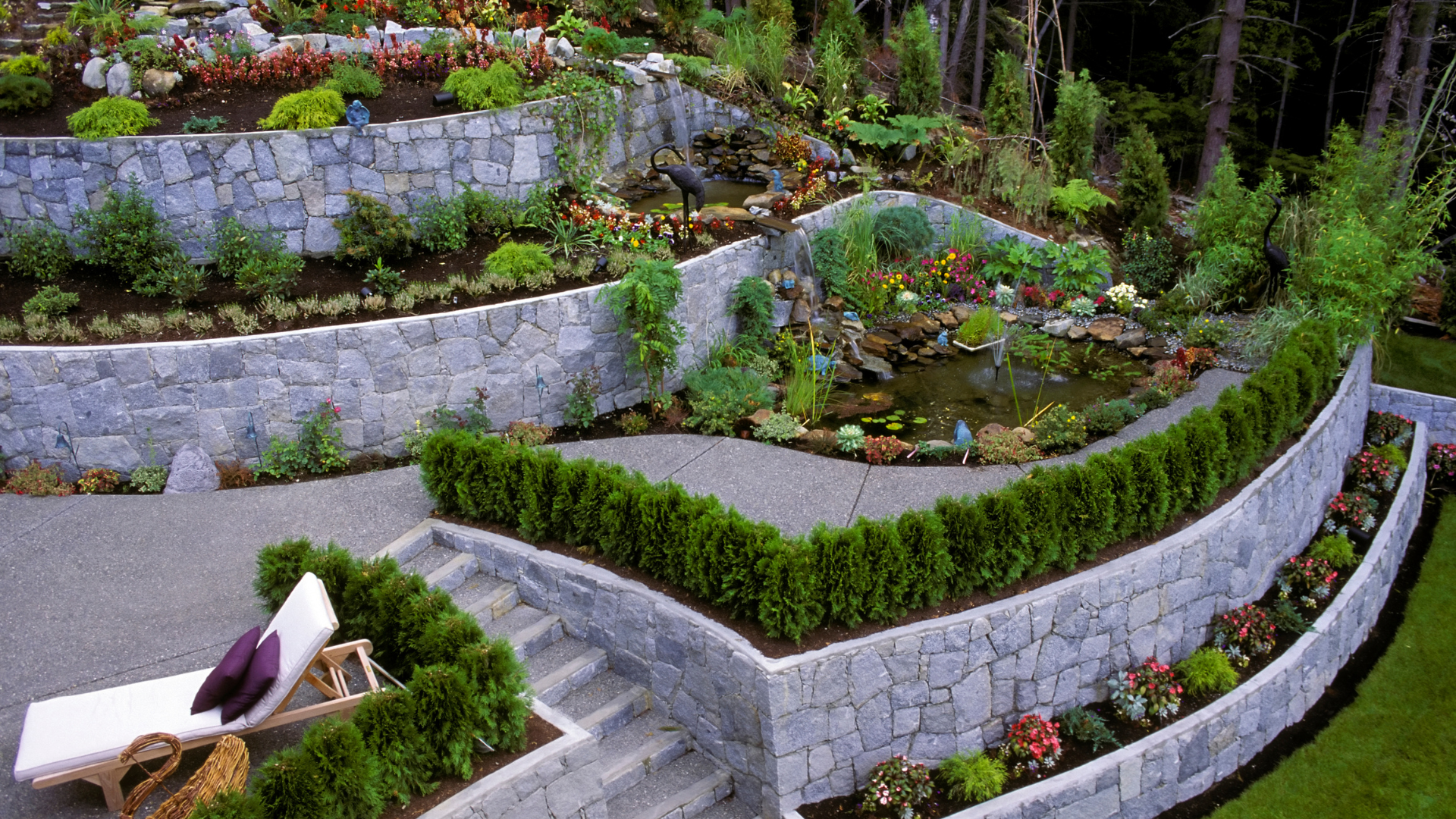 Stone terraced garden with a pond and lush greenery.