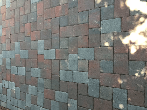 Brick pavement with reddish-brown and gray rectangular bricks in a random pattern.